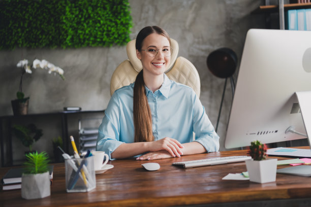 甜美迷人的女士助手照片，穿着衬衫，戴着眼镜，微笑着交流着室内工作场所工作站的现代小工具图片下载
