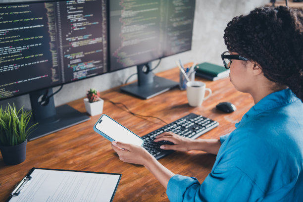 年轻女子的照片打字键盘持有设备白色屏幕穿蓝色衬衫现代办公室程序员阁楼房间室内室内工作空间图片下载