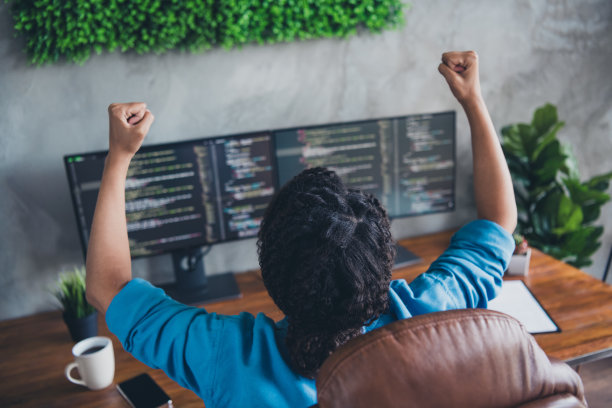 迷人的年轻女子获胜的照片举起拳头编码监视器穿蓝色衬衫现代办公室程序员室室内室内工作空间图片下载