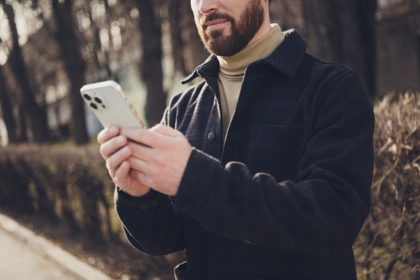 照片中英俊的成熟男子穿着时髦的衣服，使用设备走在户外的城市街道，秋天的一天图片下载