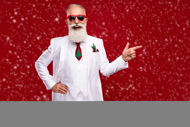 照片上白发苍苍的快乐老人指着空旷的空间，戴着圣诞树，打着圣诞的领带，孤立在红色的背景上图片下载