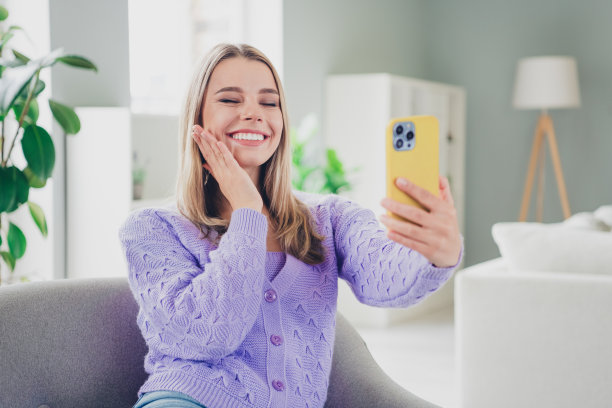 可爱开朗的女孩照片坐在扶手椅可爱的自拍照片穿着紫色的衣服花消遣宽敞的房子室内房间图片下载