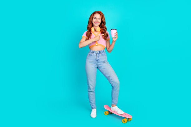 迷人的年轻女子的全身照片点喝咖啡pennboard穿着时尚的粉红色衣服孤立在青色背景图片下载