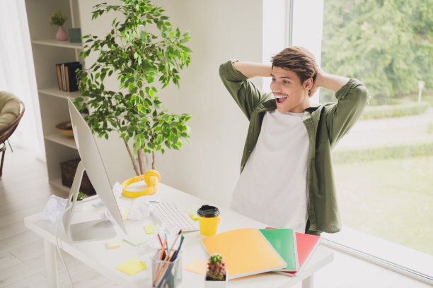 年轻成功的企业家坐在椅子上，手在头后面的现代工作站室内工作空间的照片图片下载