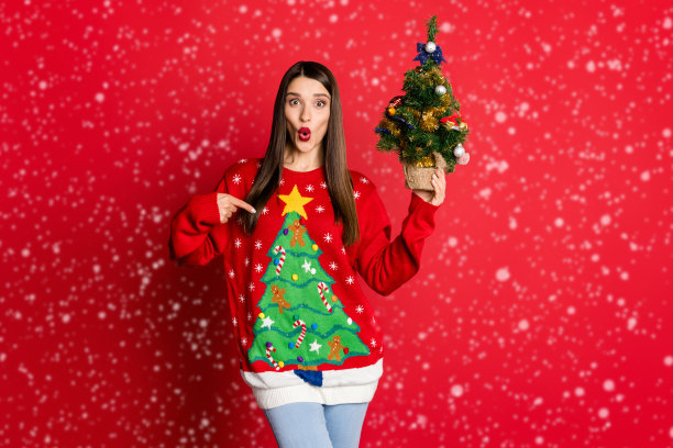 激动的女士拿着常青树的照片直接手指毛衣点缀在红色的背景上比较孤立图片下载