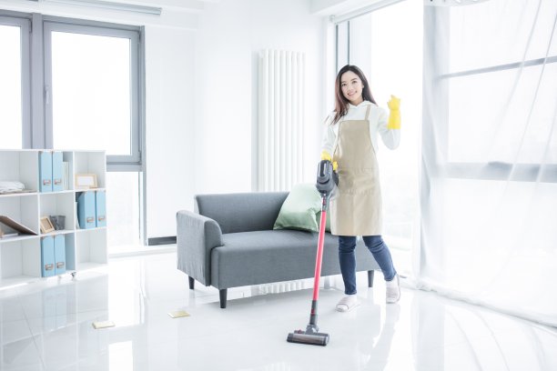 在客厅用吸尘器吸尘的亚洲女人图片下载