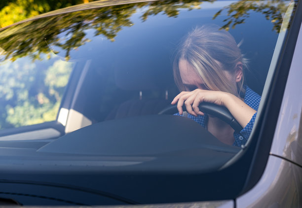 劳累过度或疲惫不堪的女司机在方向盘上睡着了，疲惫的女孩。感觉压力。图片下载