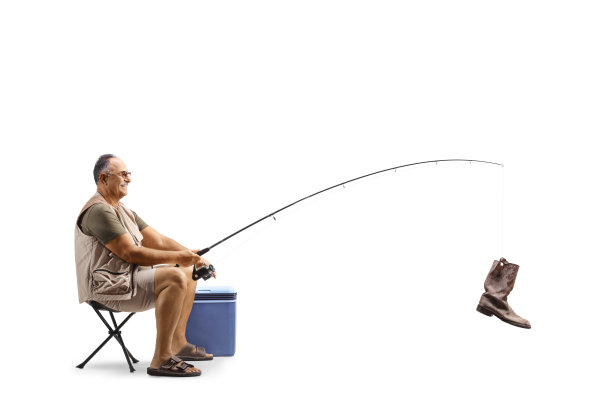 渔夫坐着钓到一只旧靴子的全身照图片下载