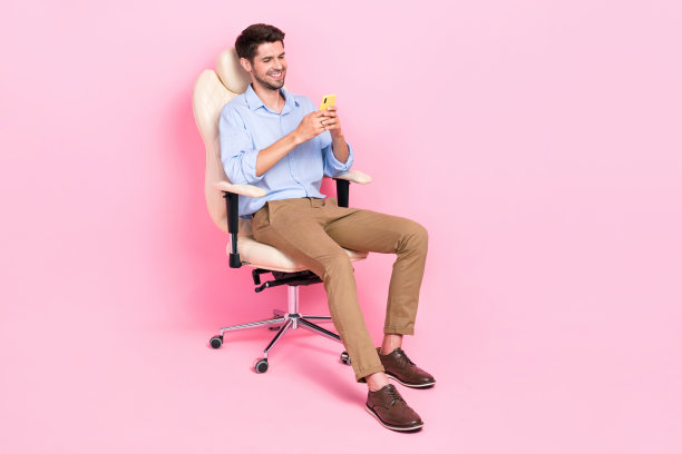 成功人士坐在自己的办公室用iphone小工具打字同事的全身照片，空白的空间被隔离在粉红色的背景上图片下载