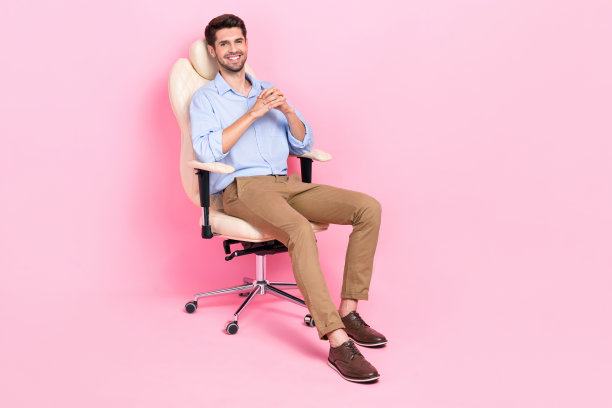 积极自信的男人坐在舒适的椅子放松休息休息暂停空白空间孤立的粉红色背景的全长照片图片下载