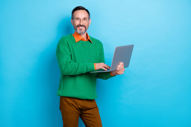 开朗的公司男子手持无线上网本的照片，在蓝色背景上露出露齿的微笑图片下载