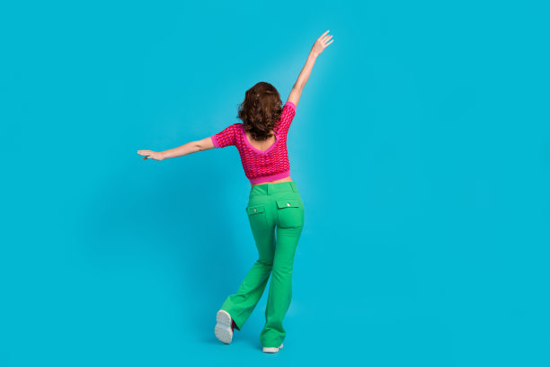 苗条可爱的漂亮女士穿着时髦的粉红色衣服的全身照片，欢乐购物销售在蓝色背景上孤立的空白空间图片下载