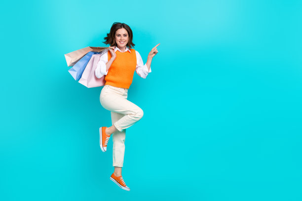 年轻快乐的女学生干部穿着制服，直接用手指空着空间，拿着购物中心孤立的青色背景图片下载