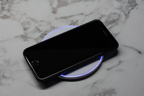 用无线感应充电器充电的黑色手机。图片下载