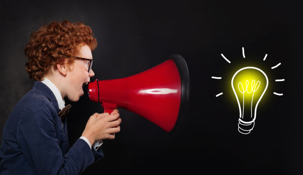 穿着校服的小男孩在黑色背景下通过红色扩音器大声尖叫。理念，成功与教育理念图片下载