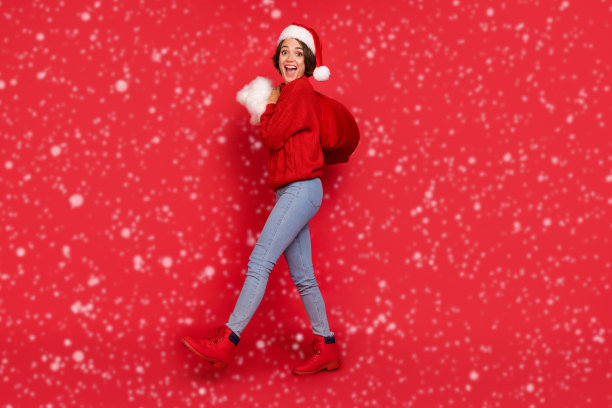 全身尺寸的照片漂亮的女人在头饰携带袋与礼物孤立生动的红色背景图片下载