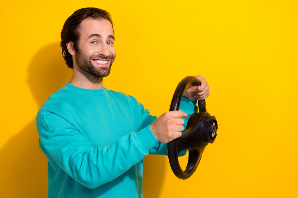 照片满意的积极经验丰富的专业出租车司机年轻人微笑着握住方向盘长路孤立的黄色背景图片下载