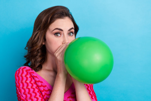 漂亮迷人的女士拿着气球准备庆祝情人节纪念日的特写照片，在蓝色的背景上孤立图片下载