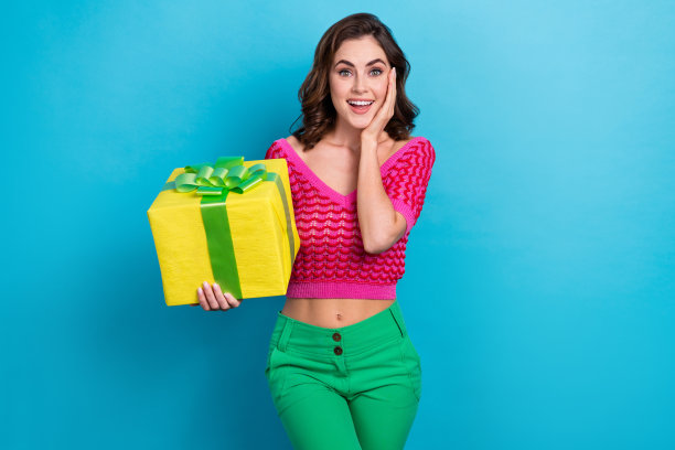 照片中，可爱的女士用手触摸脸颊，出乎意料地收到了蓝色背景的精美礼盒图片下载