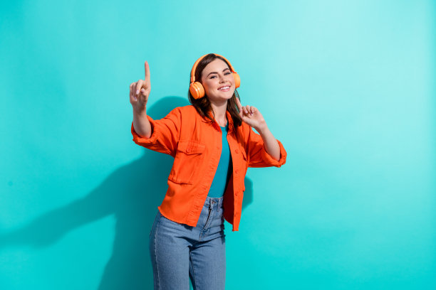 照片中，开朗可爱的女士穿着时尚的橙色服装，有乐趣，有好心情，在海蓝宝石的背景下庆祝节日图片下载