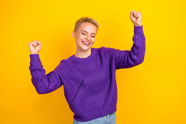 照片中开朗满意的女孩，短发，穿着针织毛衣，举手尖叫，孤立在黄色背景上图片下载