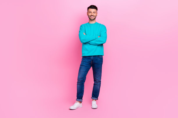 年轻的好男人的全身照片折叠双手促销员专业专家穿着时尚的蓝色看起来孤立在粉红色的背景图片下载