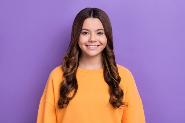 照片中开朗可爱的女士穿着冬天舒适的衣服，露齿微笑，好心情孤立在紫色的背景图片下载