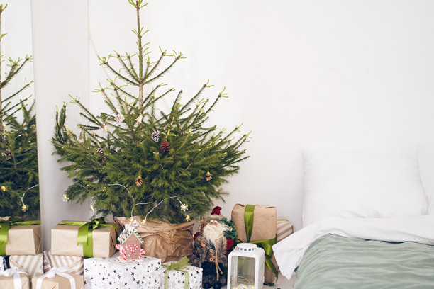 卧室里的圣诞装饰有圣诞树，用回收纸包装的礼物，手工和印有蝴蝶结的纸，圣诞老人玩具，床，枕头。带有复制空间的背景。模板，模拟为您的设计，艺术图片下载