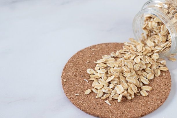 装在罐子里的燕麦片(干燕麦片)洒在白色大理石厨房桌子上图片下载
