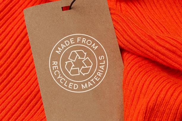 近距离的服装标签与回收图标。回收产品的概念。零浪费，可持续生产，环保和再利用理念。图片下载