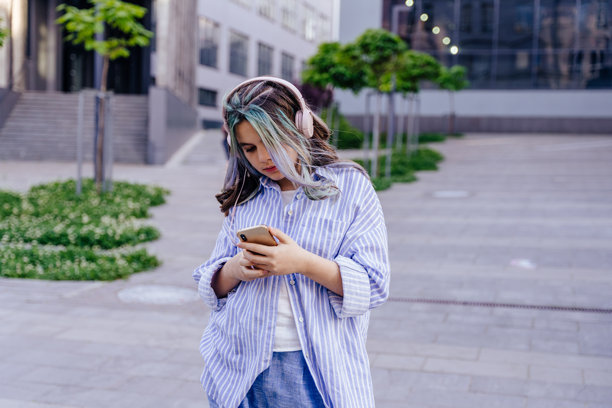 女孩戴着耳机和智能手机听音乐在户外跳舞的照片图片下载