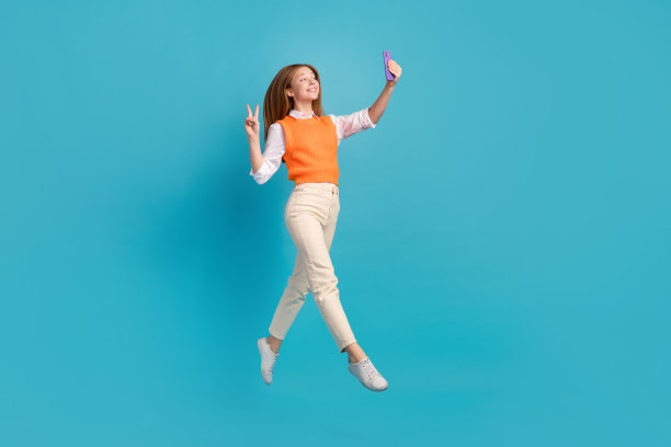 迷人的博主学生穿着马甲的照片记录视频使自拍照片脸v字空白空间孤立在蓝色背景图片下载