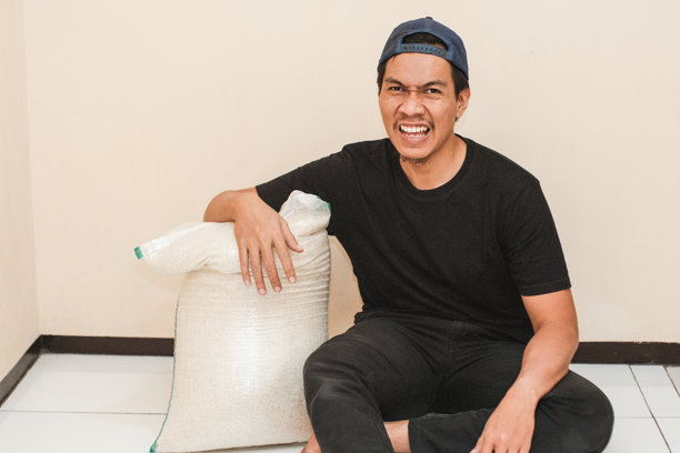 一名东南亚男子在搬运完一袋大米后疲惫不堪图片下载