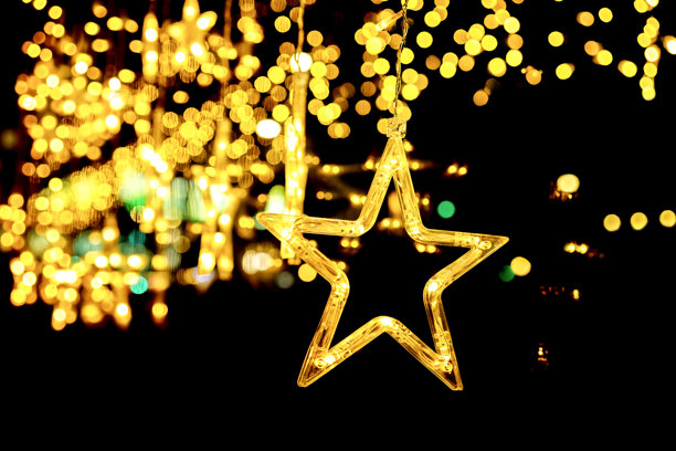 闪烁的金色星形灯光悬挂在温暖的散景背景下。哑光遮罩背景。图片下载