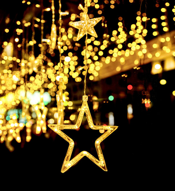 闪烁的金色星形灯光悬挂在温暖的散景背景下。哑光遮罩背景。图片下载