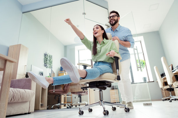 两位商务人士的照片，男性向前推椅子，女性在办公室举手图片下载