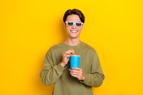 穿着时尚卡其色衣服的快乐男人，享受闲暇时光，心情愉悦，背景为黄色。图片下载