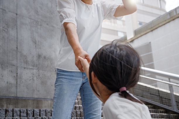 一位女士正在拉着她孩子的手爬楼梯。我急忙去引导她。图片下载