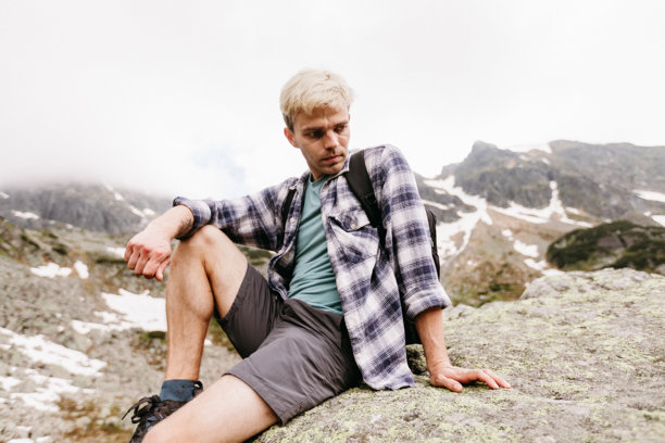 山中旅行者的照片。徒步旅行的肖像摄影。男人坐在美丽自然中的岩石上。旅行概念图片。人坐在岩石上。图片下载