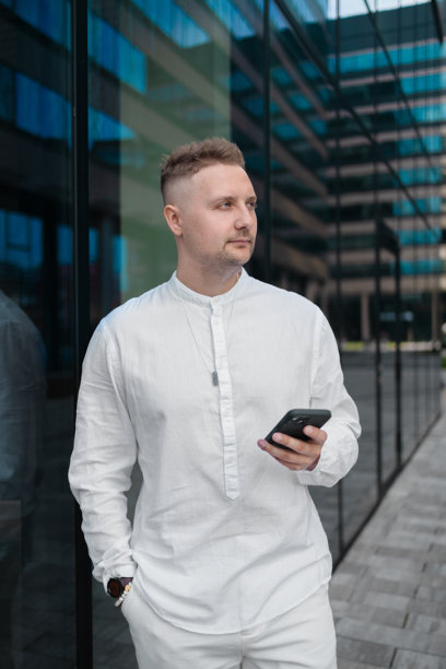 专注的年轻企业员工投资者在商业中心附近走动并使用手机。图片下载