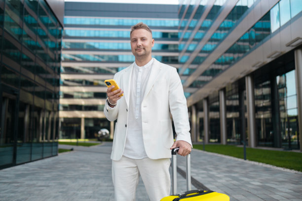 专注的年轻企业员工投资者在商业中心附近走动并使用手机。图片下载