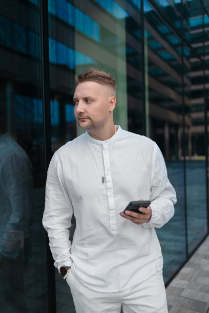 专注的年轻企业员工投资者在商业中心附近走动并使用手机。图片下载