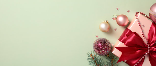 时尚的圣诞横幅模板，配有礼品盒、节日圣诞球、松枝和装饰，背景为柔和的绿色。图片下载