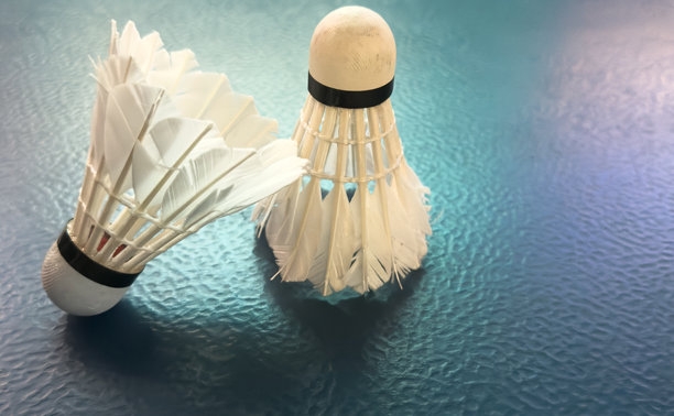 破损的羽毛球拍和使用过的白色羽毛球放在紫色的球场地板上，柔和且选择性对焦，面向全球羽毛球爱好者的概念。图片下载