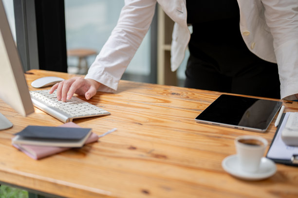 一位女商人在桌子上站着，专注地在电脑键盘上打字的特写照片。图片下载