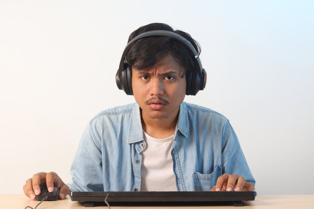 监视器视角的亚洲男性在电脑上玩视频游戏。兴奋的玩家享受乐趣。图片下载