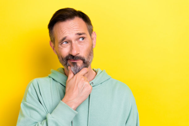 中年退休老人的肖像照片，手托下巴，嘴唇撅起，目光空洞，选择产品，背景为黄色。图片下载