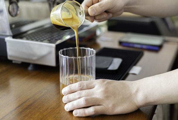 咖啡师将咖啡从壶中倒入咖啡杯。图片下载