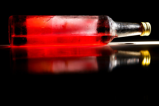 一个玻璃饮料瓶躺在地上，地上反射着一个玻璃饮料瓶。图片下载