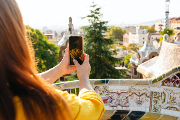 红发女性在古埃尔公园拍摄巴塞罗那的照片。旅行、旅游、科技和城市度假的概念。背影。阳光明媚的城市日子。图片下载
